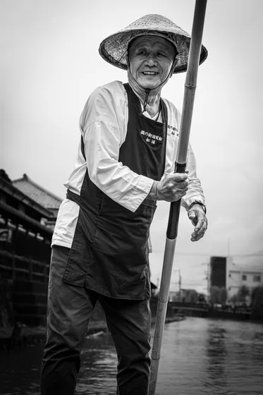 The same boatman looking into the lens, the river behind him