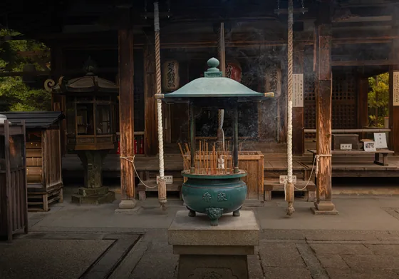 A bronze incense burner standing before a dark temple front